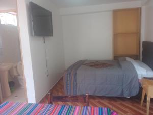 1 dormitorio con 1 cama y TV de pantalla plana en Hostal festival, en Ollantaytambo