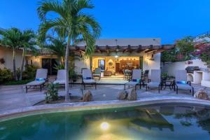 un patio trasero con piscina, sillas y una casa en Chris Casa del Sol San José del Cabo, 5 Bedroom Private Pool and Spa en San José del Cabo