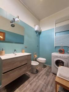 a bathroom with a toilet and a sink and a washing machine at Rustico Via del Sole 13 in Amandola