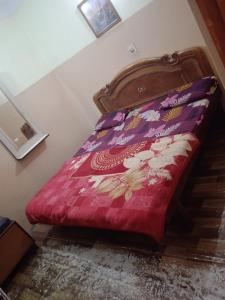 a bed with a red comforter on it in a room at Aman guest house in Katra