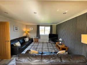 a living room with a leather couch and a television at Drumhead Cottage Finzean, Banchory Aberdeenshire Self Catering with Hot Tub in Finzean