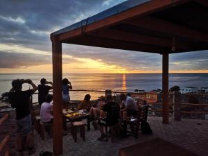 een groep mensen die aan een tafel zitten en naar de zonsondergang kijken bij Kaza Ladera in Seladinha
