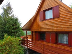 Cabaña de madera con ventanas rojas y porche en Lili's Lovely Log Home in the Forest, en Bükkszentkereszt
