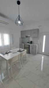 a white kitchen with a white table and chairs at Lava Guesthouse Prive in Karterados