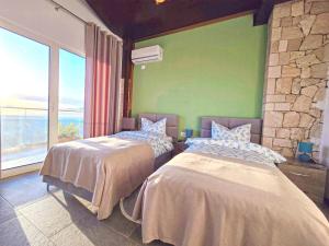 - 2 lits dans une chambre avec une grande fenêtre dans l'établissement Pamja e Qyteteve, à Krujë