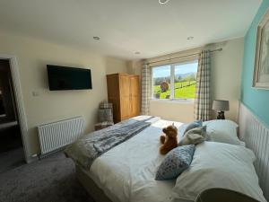 un osito de peluche sentado en una cama en un dormitorio en Drumhead Cottage Finzean, Banchory Aberdeenshire Self Catering with Hot Tub, en Finzean