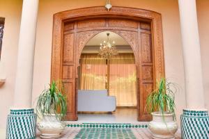 een grote houten deur met twee planten ervoor bij Villa in Central Marrakesh in Marrakesh