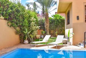 Villa in Central Marrakesh في مراكش: فناء فيه كرسيين ومسبح