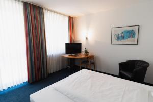 a hotel room with a bed and a desk with a computer at Hotel am Weiher in Erkelenz