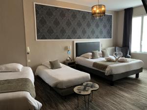 ロシュフォールにあるHotel de France Citotelのベッド2台とテーブルが備わるホテルルームです。