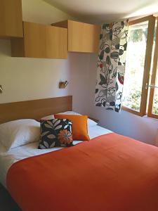 um quarto com uma cama com lençóis laranja e uma janela em Chalet Loire proche Sancerre em Cosne Cours sur Loire