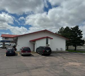a building with two cars parked in a parking lot at Mitchell Inn in Mitchell