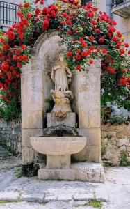 a stone fountain with red flowers on top of it at Affittacamere La Cartiera in Palazzo Adriano +10 photos