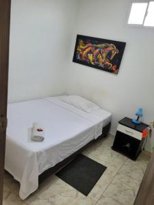 białe łóżko w pokoju ze zdjęciem na ścianie w obiekcie HOSTAL S Y S w mieście Cali