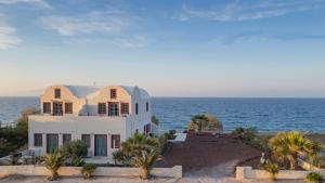 a white house with the ocean in the background at Michelangelo Beach Villa in Oia