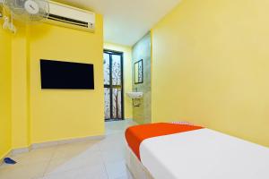 Habitación amarilla con cama y ventilador. en De Mawardah Inn Hotel en Melaka