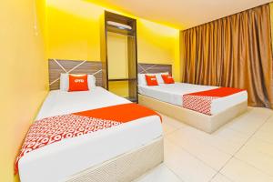 2 camas en una habitación de color amarillo y naranja en De Mawardah Inn Hotel en Melaka