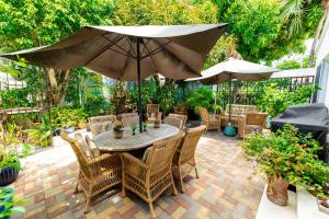 een patio met een tafel en stoelen en een parasol bij Antigua Village Beach Resort in Saint Johnʼs