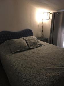1 cama en un dormitorio con una lámpara en la pared en 114 Village de Campagne - FONT MOURIER en Cogolin