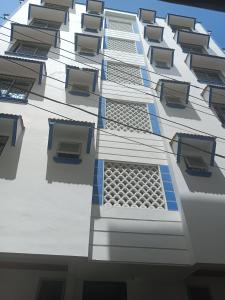 un grand bâtiment blanc avec des fenêtres latérales dans l'établissement Royals apartment, à Mombasa