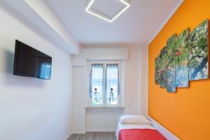 a bedroom with an orange accent wall and a flat screen tv at Per le vie del Conero in Sirolo