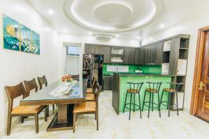 una cocina con mesa y sillas y una cocina con armarios verdes en Villa FLC Sầm Sơn Sao Biển SB106, en Thanh Hóa