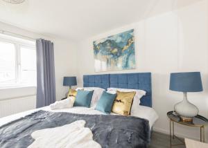 ein Schlafzimmer mit einem großen blauen Bett mit Kissen in der Unterkunft Voguish 3BR Home in Huyton in Liverpool