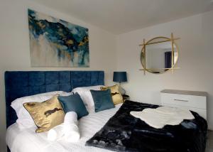 Voguish 3BR Home in Huyton في ليفربول: غرفة نوم مع سرير مع اللوح الأمامي الأزرق والوسائد