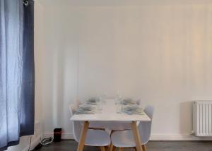 Voguish 3BR Home in Huyton في ليفربول: طاولة بيضاء عليها كراسي وصحون وكاسات