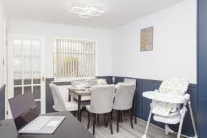 a dining room with a table and chairs and a laptop at Urban Gem in Longbridge