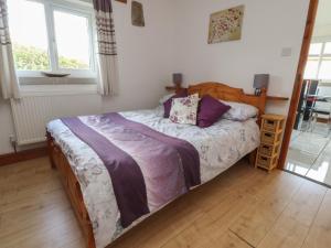 a bedroom with a bed with purple blankets and pillows at Pendleside in Chatburn