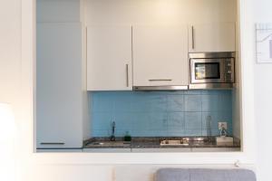 a kitchen with white cabinets and blue tiles at Carla,centro Llanes a 350m playa in Llanes