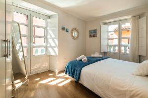 a bedroom with a large white bed and two windows at Carla,centro Llanes a 350m playa in Llanes