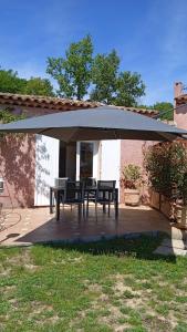 un patio con una mesa bajo una sombrilla en T2 au calme avec piscine, en Néoules