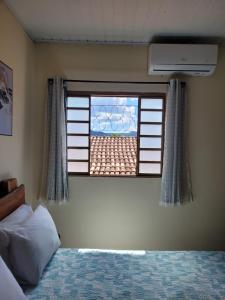 a bedroom with a bed and a window with a view at Suítes Boa Viagem in Pirenópolis