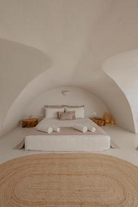 a bedroom with a white bed with pillows at Michelangelo Beach Villa in Oia