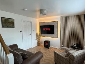 ein Wohnzimmer mit einem Sofa und einem TV in der Unterkunft Durham Dales Luxury Cottage in Stanhope