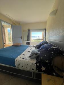 a bedroom with a large bed with blue comforter and pillows at F2 apartments with panoramic sea views in Farinole