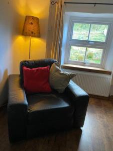 a black leather couch in a room with a window at Mill Cottage, Upper Hulme in Upper Hulme