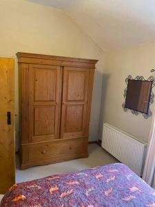 a bedroom with a wooden cabinet and a bed at Mill Cottage, Upper Hulme in Upper Hulme