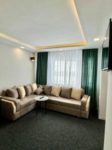 uma sala de estar com um sofá e cortinas verdes em Garden Hotel em Akhalk'alak'i