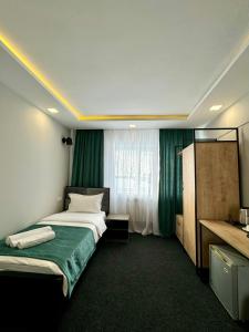 um quarto de hotel com uma cama e uma colcha verde em Garden Hotel em Akhalk'alak'i