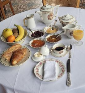 uma mesa branca com comida para o pequeno almoço e café nela em Castel Saint Laurent em Langeais