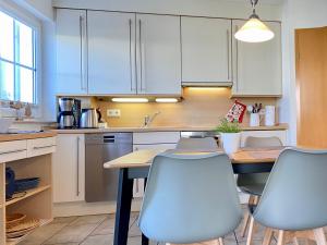 a kitchen with white cabinets and a table and chairs at Dünenresidenz Karlshagen - Ferienwohnung Lindenweg 8b in Ostseebad Karlshagen