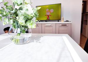 a vase of flowers sitting on a table with a television at Aida Guest House - Decimomannu in Decimomannu +2 photos