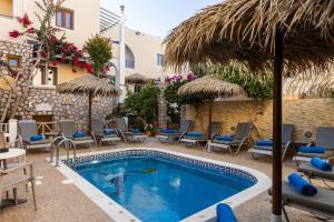 a pool with chairs and umbrellas next to a building at Polydefkis Hotel in Kamari