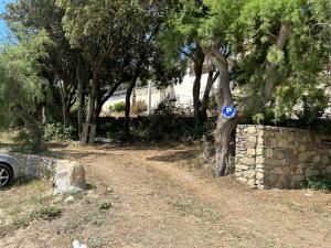 a dirt road with a blue sign on a tree at appartement 2 bord de mer in Farinole