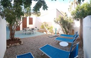 a patio with blue chairs and a table and a tree at Villa Dacla in Lampedusa