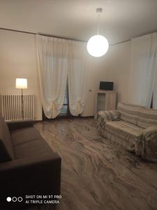 a bedroom with a bed and a couch and curtains at Ampio appartamento fino a 9 ospiti in Porto San Giorgio