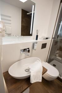 a white bathroom with a sink and a toilet at Hotel Haus Delecke in Möhnesee
